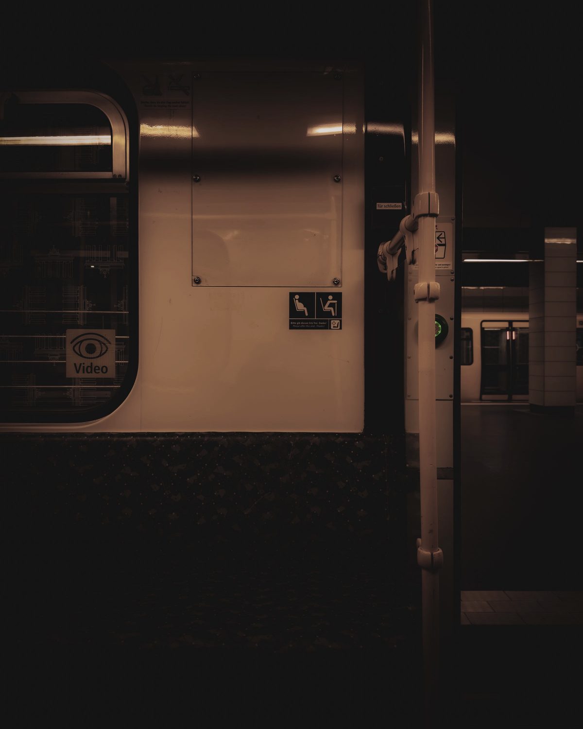 An empty carriage doorway on a station platform at night, nobody aboard.